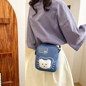 Detalle de un bolso bandolera de nailon azul con un lindo diseño de gato de peluche