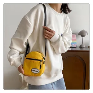 Primer plano de un mini bolso bandolera de nailon amarillo con sudadera blanca