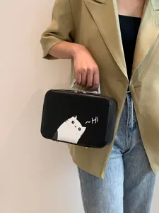 Détail d'une trousse de maquillage noire avec imprimé chat mignon tenue à la main