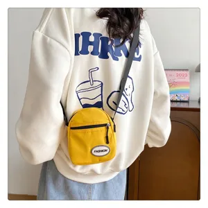 Vista detallada de un pequeño bolso bandolera de nailon amarillo para móvil en una sudadera