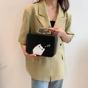 Trousse de maquillage noire élégante avec imprimé chat de dessin animé, tenue par modèle
