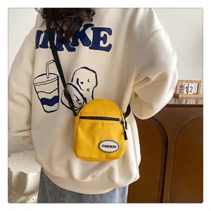 Primer plano de un mini bolso bandolera de nailon amarillo usado por una modelo casual.