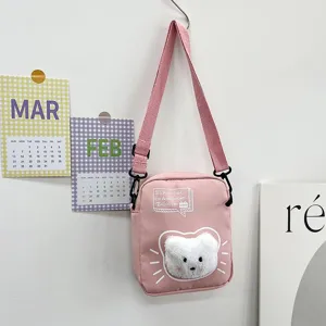 Vista detallada de un lindo bolso bandolera de nailon rosa con un gato de peluche 3D.