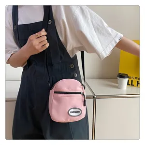 Primer plano de un bolso bandolera de nailon rosa con un peto negro informal