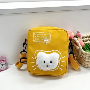 Detalle de bolso bandolera de nailon amarillo con diseño de un osito blanco y esponjoso