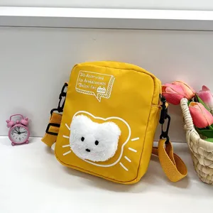 Vista detallada de un bolso bandolera de nailon amarillo con una linda cara de gato de felpa