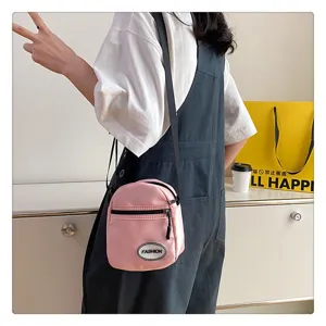 Vista detallada de un mini bolso bandolera de nailon rosa llevado por una modelo