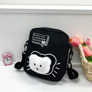 Primer plano de un bolso bandolera de nailon negro con diseño de gato y flores rosas