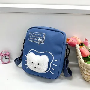 Vista detallada de la cabeza de gato de peluche blanco en un bolso bandolera de nylon azul.