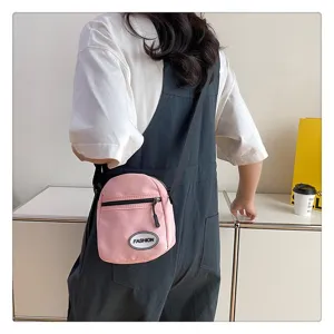 Bolso bandolera pequeño de nailon rosa con etiqueta de moda en la espalda del modelo.