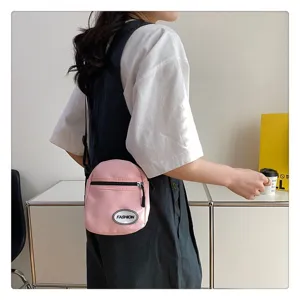 Primer plano de un mini bolso bandolera de nailon rosa llevado por una estudiante con ropa casual