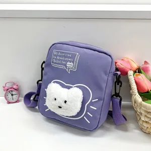 Primer plano de bolso bandolera de nailon morado con aplique de gato blanco.