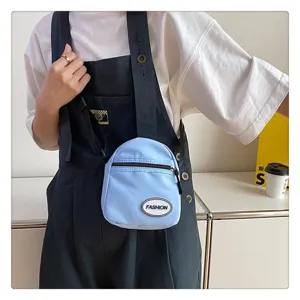 Bolso bandolera de nailon azul claro sobre un mono vaquero de color oscuro