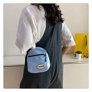 Vista detallada del pequeño bolso bandolera de nailon azul claro con ropa casual