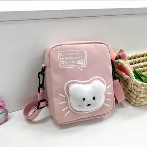 Vista detallada de un bonito bolso bandolera de nailon rosa con un oso de peluche.