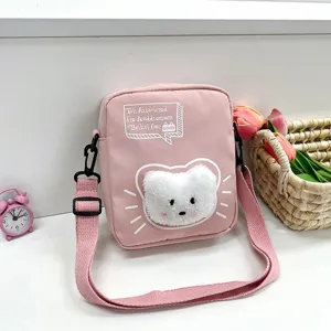 Primer plano de un bolso bandolera de nailon rosa con un gato de peluche y correa