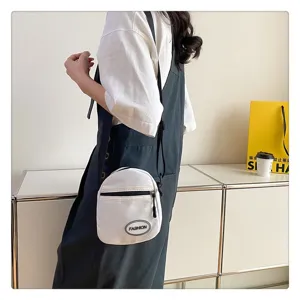 Detalle de una modelo que luce un pequeño bolso bandolera de nailon color blanco