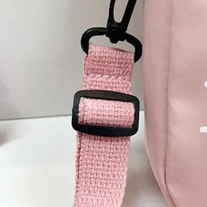 Primer plano de la correa de nailon duradera y la hebilla negra ajustable en bolso rosa.