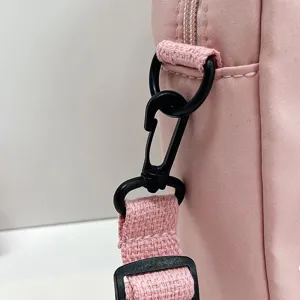 Detalle del robusto gancho giratorio de plástico negro en un bolso de nailon rosa.