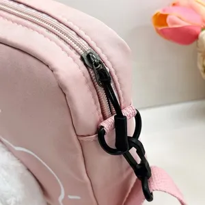 Detalle de la cremallera y el enganche de la correa en un bolso bandolera de nailon rosa gato