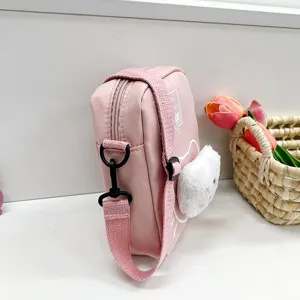 Vista lateral de un bolso bandolera de nailon rosa con decoración de cabeza de gato