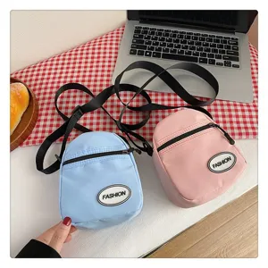 Primer plano de bolsos bandolera de nailon azul claro y rosa sobre un mantel de cuadros