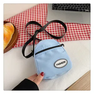 Primer plano de un bolso bandolera de nailon azul claro sobre un mantel de cuadros rojos