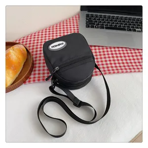 Detalle de un bolso bandolera pequeño de nailon negro ligero de estilo japonés casual.