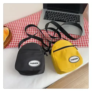 Dos bolsos bandolera ligeros de nailon en negro y amarillo en un escritorio de estilo