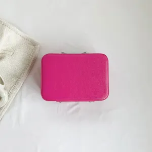Vue détaillée de dessus d'une boîte à maquillage en cuir rose fuchsia sur fond de tissu blanc