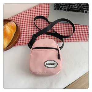 Detalle del bolso bandolera de nailon rosa sobre un fondo de tela a cuadros rojos
