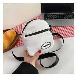 Detalle de un pequeño bolso bandolera de nailon blanco minimalista para uso diario