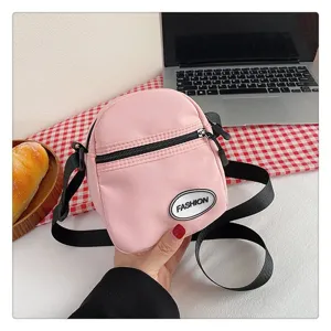 Bolso bandolera pequeño de nailon rosa con parche de moda y correa negra ajustable.