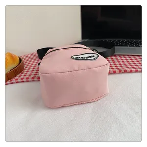 Vista detallada de un bolso bandolera de nailon rosa con parche Fashion y cremallera negra.