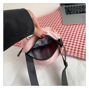 Vista interior detallada de un bolso bandolera de nylon rosa con forro gris