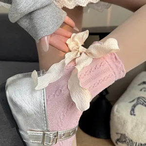 Close-up of pink mid-calf socks with cream bow and delicate lace pattern detail