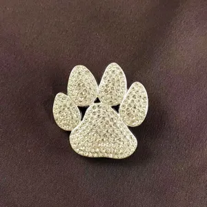 Detailed macro view of a sparkling rhinestone paw-shaped brooch with silver-tone finish