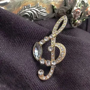 Macro detail view of a vintage gold treble clef brooch with sparkling rhinestones.