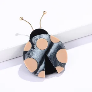 Broche de escarabajo artístico en resina marmoleada con lunares beige y antenas doradas