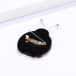 Reverso de un lindo broche de mariquita en acrílico negro con pasador de seguridad dorado.