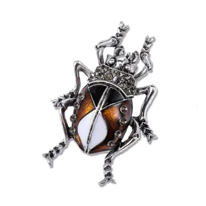 Macro detail view of vintage beetle brooch featuring grey crystals and amber enamel
