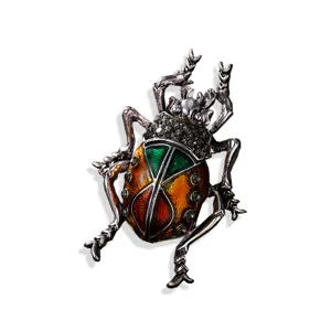 Vintage beetle insect brooch with colorful enamel and grey crystals on white background.
