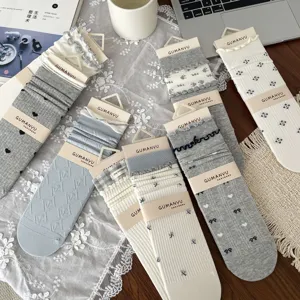 Assorted collection of sweet Japanese-style floral and ruffled mid-calf socks on a wooden desk.
