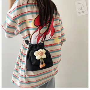 Rückansicht einer süßen schwarzen Canvas-Umhängetasche im japanischen Stil mit Blumenanhänger.