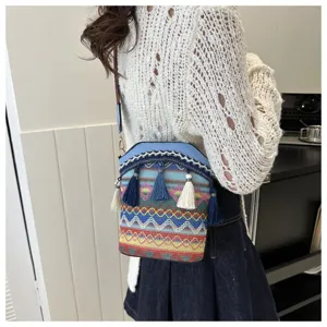 Detailansicht einer gewebten Beuteltasche im Ethno-Stil mit Quasten, getragen von einem Modell