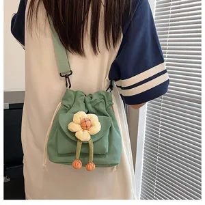 Detailansicht einer süßen grünen Canvas-Umhängetasche mit Blumenanhänger am Modell