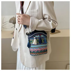 Modell trägt eine gewebte Beuteltasche im ethnischen Stil mit bunten Quastendetails