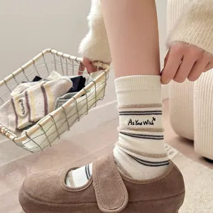 Close-up of creme striped socks with As You Wish embroidery and brown suede shoe