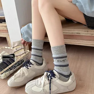 Close-up of grey striped crew socks with 'As You Wish' embroidery detail and soft texture