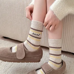 Close-up detail of warm striped socks featuring 'As You Wish' embroidery on a cozy rug.